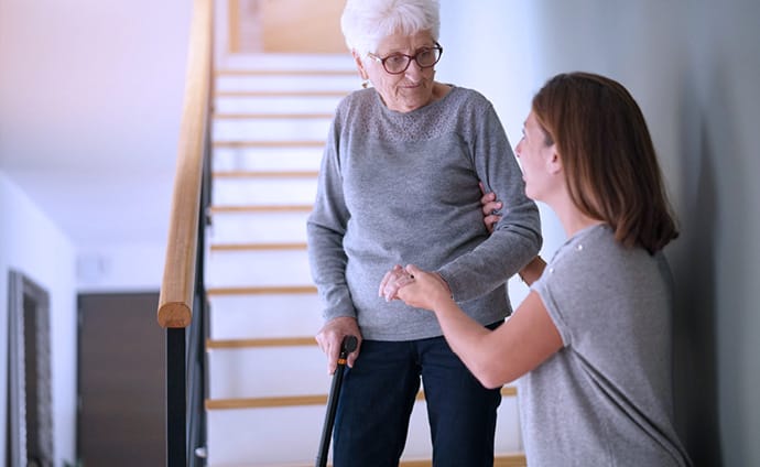 Elderly lady being helped down the stairs during a physio falls prevention assessmentt
